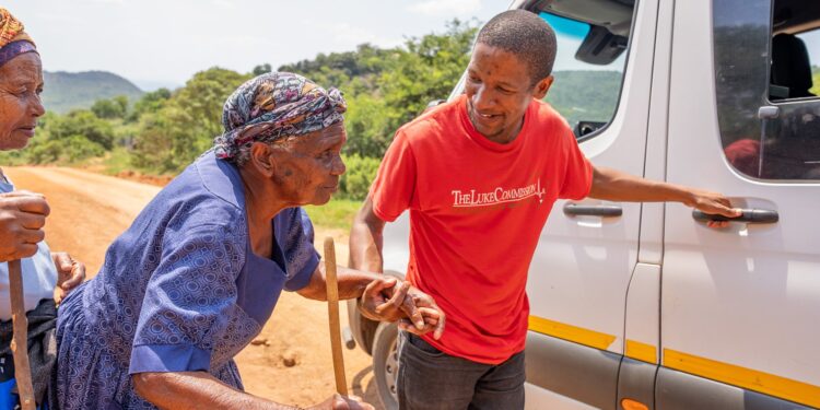 An attendant from the Luke commission assisting an elderly woman.