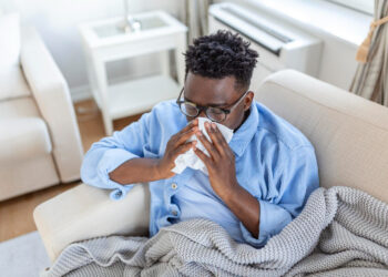 A young man experiencing flu symptoms, taking rest at home.