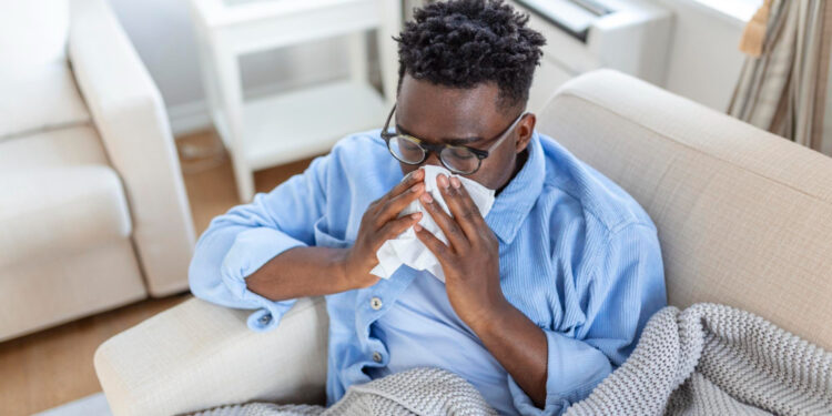 A young man experiencing flu symptoms, taking rest at home.