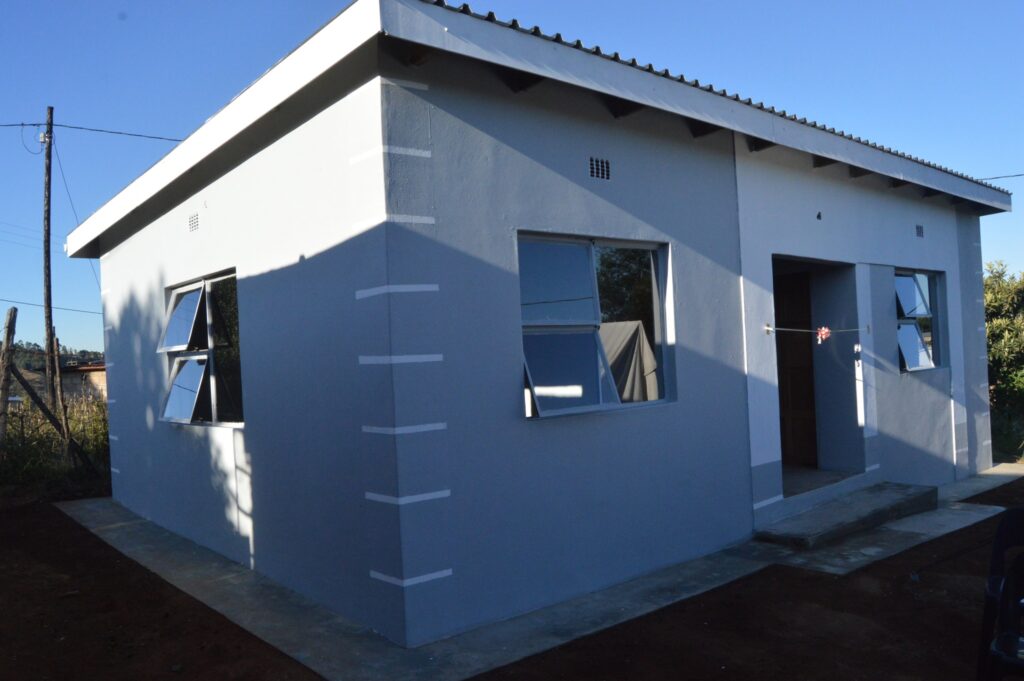 Deputy Prime Minister Thulisile Dladla hands over house keys to Gogo Khumbulile Dlamini in Mpolonjeni, one of four beneficiaries of newly built homes in the Hhohho region. Looking on are Motshane MP Wilton Nkambule and NDMA officials.