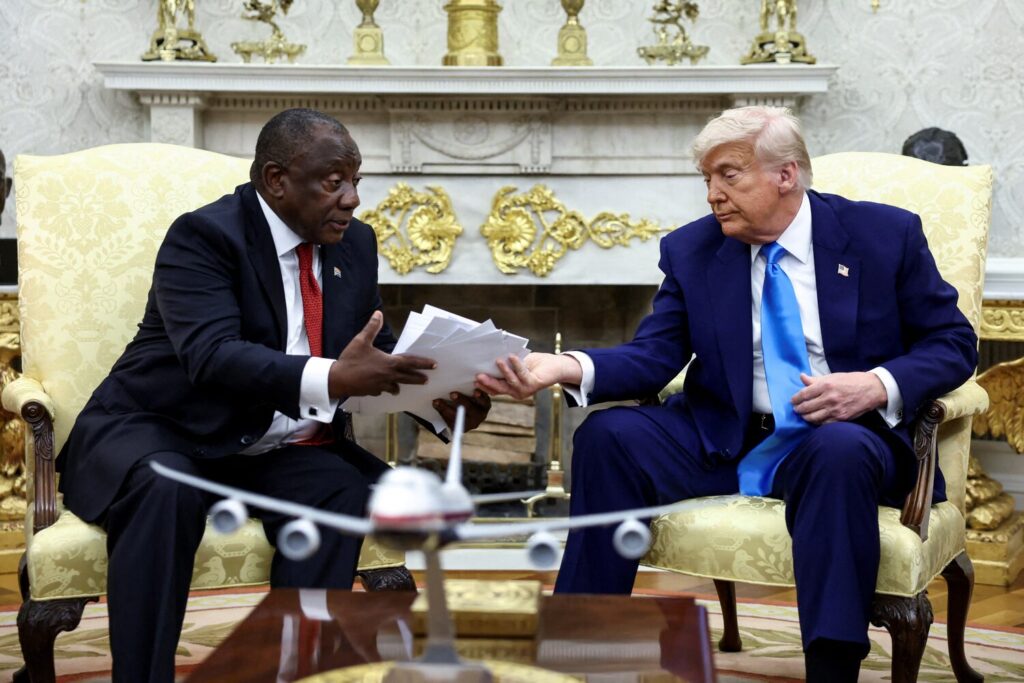 U.S. President Donald Trump hands over to South African President Cyril Ramaphosa copies of articles that he said showed white South Africans who had been killed, in the Oval Office of the White House in Washington, D.C., U.S., May 21, 2025. REUTERS/Kevin Lamarque