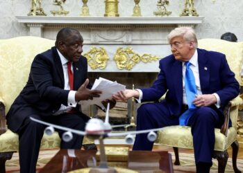 U.S. President Donald Trump hands over to South African President Cyril Ramaphosa copies of articles that he said showed white South Africans who had been killed, in the Oval Office of the White House in Washington, D.C., U.S., May 21, 2025. REUTERS/Kevin Lamarque