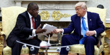 U.S. President Donald Trump hands over to South African President Cyril Ramaphosa copies of articles that he said showed white South Africans who had been killed, in the Oval Office of the White House in Washington, D.C., U.S., May 21, 2025. REUTERS/Kevin Lamarque