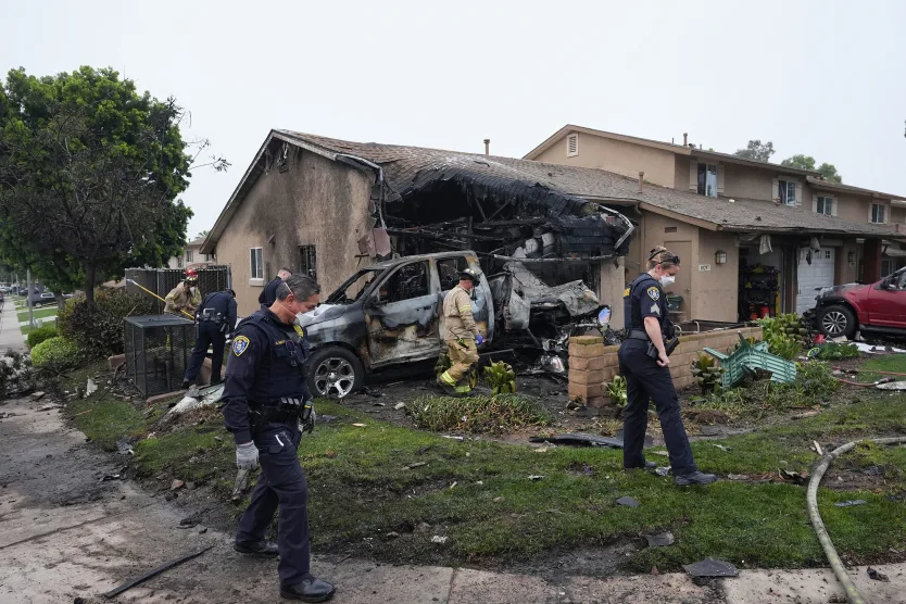 Authorities work the scene where a small plane crashed into a San Diego neighborhood, setting several homes on fire and forcing evacuations along several blocks early Thursday. Gregory Bull/AP