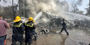 Rescue team members work as smoke rises near the crash site. Amit Dave/Reuters
