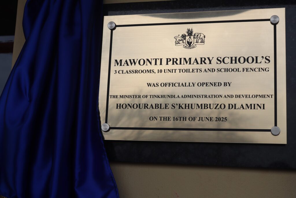A commemorative plaque mounted on the building outlines the completed RDF-funded developments, including classrooms, toilet units, and perimeter fencing at Mawonti Primary School.