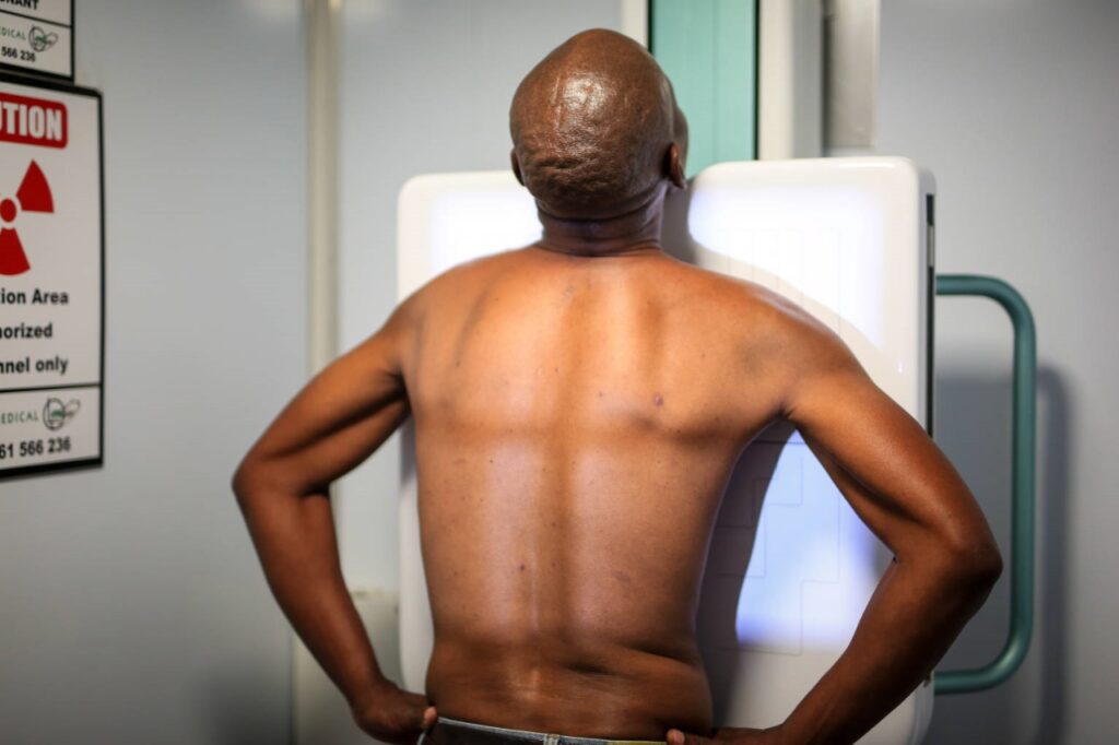 A man stands in front of an X-ray machine during a Benefit Medical Examination for ex-mineworkers