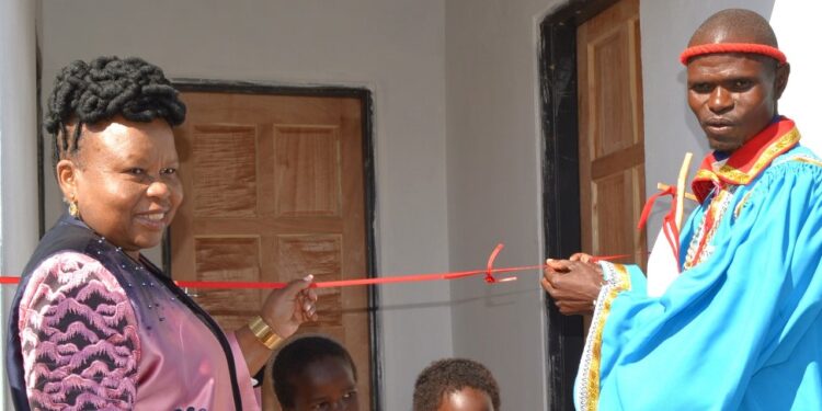 Acting Deputy Prime Minister Jane Mkhonta-Simelane cuts the ribbon to officially hand over the new house to Nkosinathi Ngwenya in Nsingweni, Maphalaleni Inkhundla.