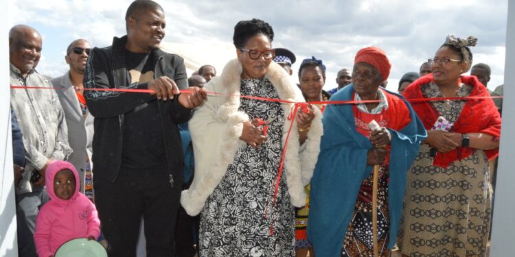 Deputy Prime Minister Thulisile Dladla cuts the ribbon during the official handover of Gogo Fakubi Mkhabela’s newly built house in Mhlumeni, joined by Chief Jozane, MP Joseph Souza, and other dignitaries.