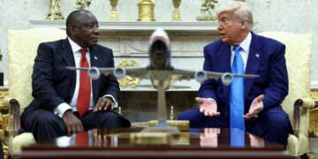U.S. President Donald Trump hands over to South African President Cyril Ramaphosa copies of articles that he said showed white South Africans who had been killed, in the Oval Office of the White House in Washington, D.C., U.S., May 21, 2025. REUTERS/Kevin Lamarque