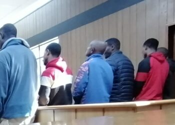 The six accused men from Mdzangwini appear in the Mbabane Magistrates Court dock facing multiple assault charges linked to a violent land dispute.