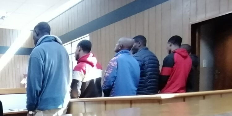 The six accused men from Mdzangwini appear in the Mbabane Magistrates Court dock facing multiple assault charges linked to a violent land dispute.
