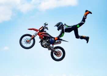A stunt biker from Jungle Rush FMX catches massive air during a jaw-dropping freestyle motocross performance.