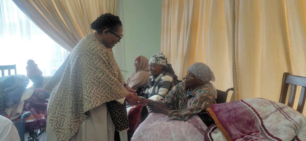 Deputy Prime Minister Thulisile Dladla presenting blankets to residents at the facility.