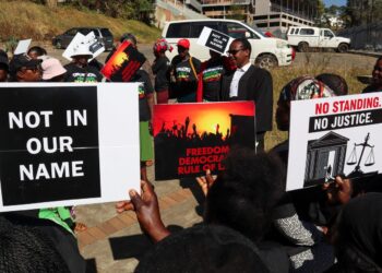Protesters hold placards as lead applicant and lawyer Mzwandile Masuku addresses them outside the court, after a hearing was postponed, in Mbabane, Eswatini, August 22, 2025. REUTERS/Zakhele Mabuza