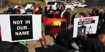 Protesters hold placards as lead applicant and lawyer Mzwandile Masuku addresses them outside the court, after a hearing was postponed, in Mbabane, Eswatini, August 22, 2025. REUTERS/Zakhele Mabuza