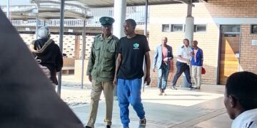Balingene Kidwell Dlamini under an HMCS officer guard after his court appearance at the Mbabane Magistrates Court. | Pic, Sithembiso Sihlongonyane