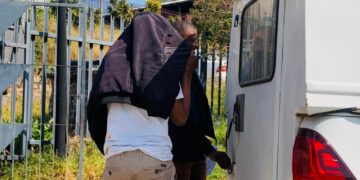 No face, just charges — Phinda Mtsetfwa, 48, hides his face with a jacket after appearing before the magistrate. He now faces two more charges, adding to a string of serious allegations, including impersonating a police officer.