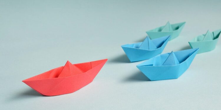 A single paper boat leads others across the water, symbolizing the journey and responsibility of leadership.