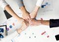 Five hands join together in unity to symbolise teamwork and shared leadership.