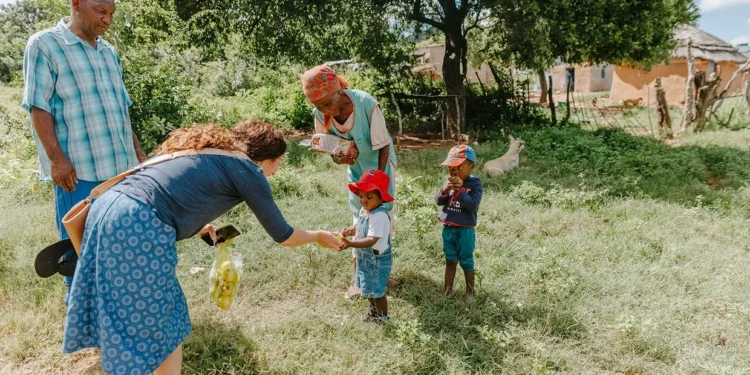 A volunteer distributes apples to children in a rural community in Eswatini. Photo by Project Love One with Mychelle LeVan and Olivia Hurtado.
