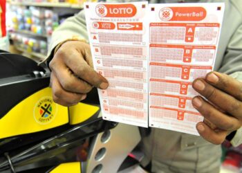 A customer holds a freshly purchased Lotto ticket