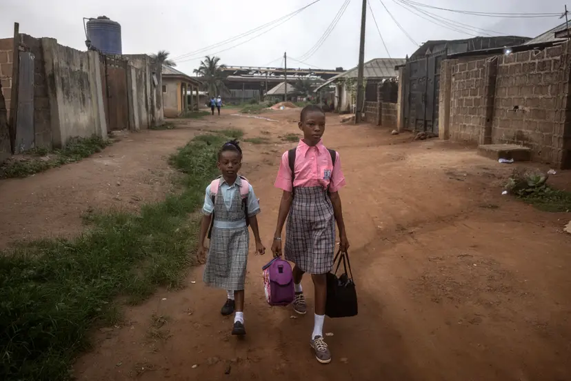 Dimimu Olasupo, 6, and her sister Ifeoluwa, 11, walk to school. Finbarr O'Reilly for The New York Times