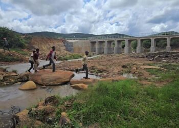 Children make their way across the river using rocks while the newly commissioned Dlomodlomo Low Level Crossing stands in the background. Photo by Microprojects MEPD.