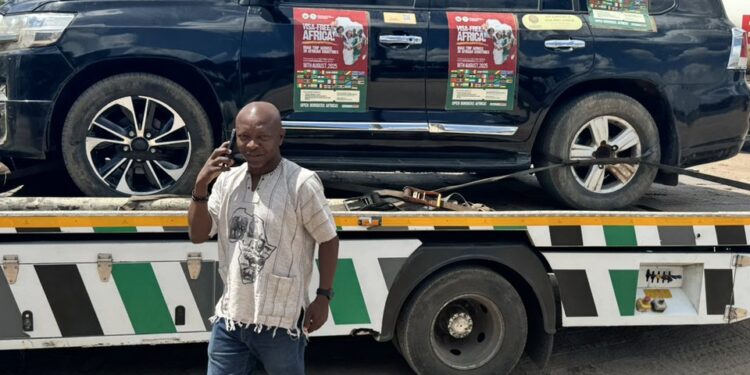 Ras Mubarak speaks on his phone beside one of the campaign’s Land Cruiser vehicles loaded onto a flatbed towing truck during the Trans Africa Tourism and Unity Campaign.