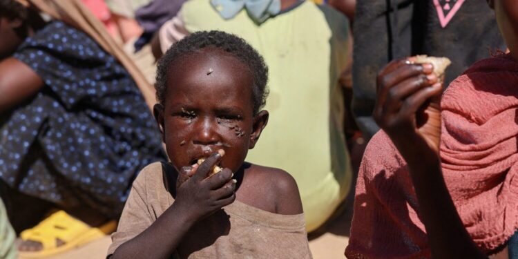 A Sudanese refugee child from Al-Fashir eats a shared a meal at the Tine transit refugee camp, amid the conflict between the paramilitary Rapid Support Forces (RSF) and the Sudanese army, in eastern Chad, November 22, 2025. REUTERS/Amr Abdallah Dalsh/File Photo
