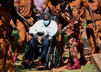 Prison warders wheel Uganda's four-time presidential candidate Kizza Besigye to the court room where he was charged alongside his colleague Obeid Lutale and Captain Denis Oola with treason at the Chief Magistrate Court in Nakawa suburb of Kampala, Uganda, February 21, 2025. REUTERS/Abubaker Lubowa/File Photo