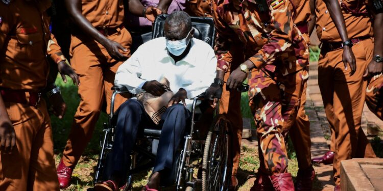 Prison warders wheel Uganda's four-time presidential candidate Kizza Besigye to the court room where he was charged alongside his colleague Obeid Lutale and Captain Denis Oola with treason at the Chief Magistrate Court in Nakawa suburb of Kampala, Uganda, February 21, 2025. REUTERS/Abubaker Lubowa/File Photo