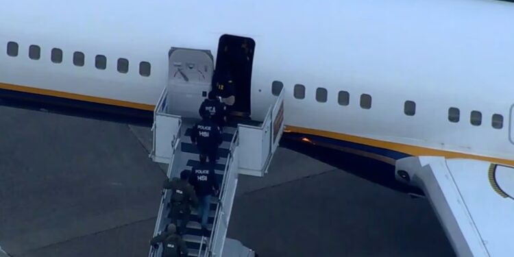 Law enforcement officials walk onto the plane carrying Venezuelan President Nicolás Maduro on Saturday. WCBS