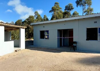 Newly constructed two-room house complete with water tank, toilet, and makeshift kitchen.