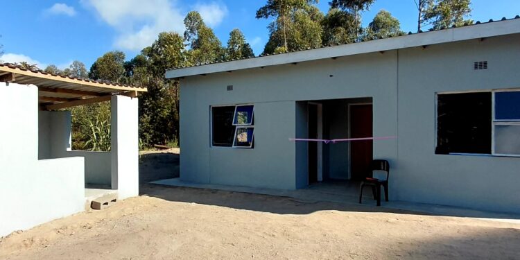 Newly constructed two-room house complete with water tank, toilet, and makeshift kitchen.