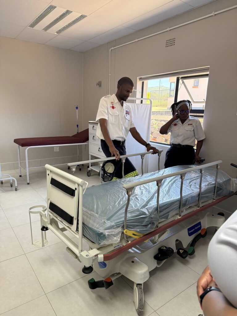 Paramedics demonstrate emergency procedures using a bed at the Mshinande Stabilization Centre during the SMVAF Board visit.