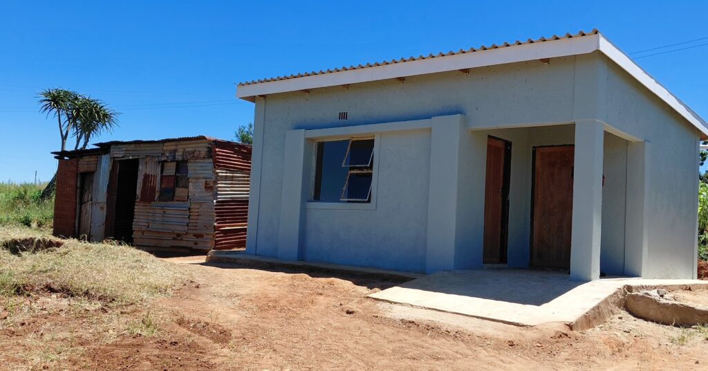 A newly constructed house provided to a vulnerable family stands in the foreground, with the family’s old unsafe structure visible in the background in one of the beneficiary communities. Photo: Deputy Prime Minister’s Office
