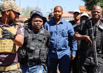 Xolani Khumalo, in blue, flanked by members of his security detail, arriving at Palm Ridge Magistrates’ Court last month on charges related to a December 2025 drug-bust operation. (Photo: OJ Koloti / Gallo Images)